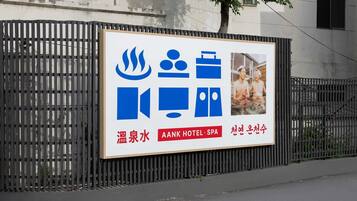 A signboard for AANK Hotel & Spa with icons indicating amenities like a sauna, massage, and swimming pool.