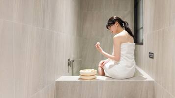 A person sitting on a bathtub in a bathroom with a towel wrapped around their body.