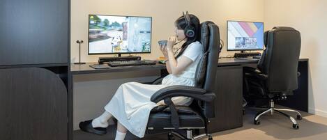 A person seated at a desk with two monitors, a keyboard, and headphones.
