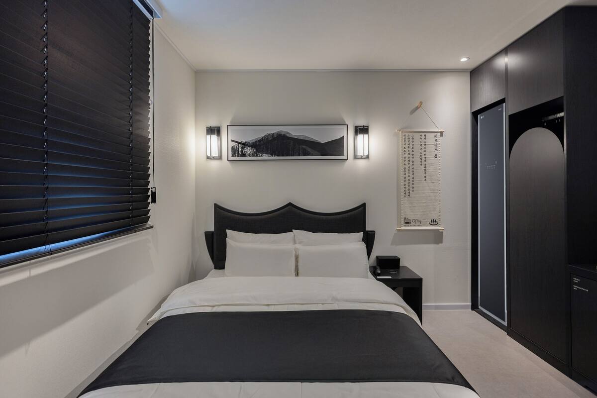 Een slaapkamer met een bed, nachtkastjes, een kunstwerk aan de muur en een deur.