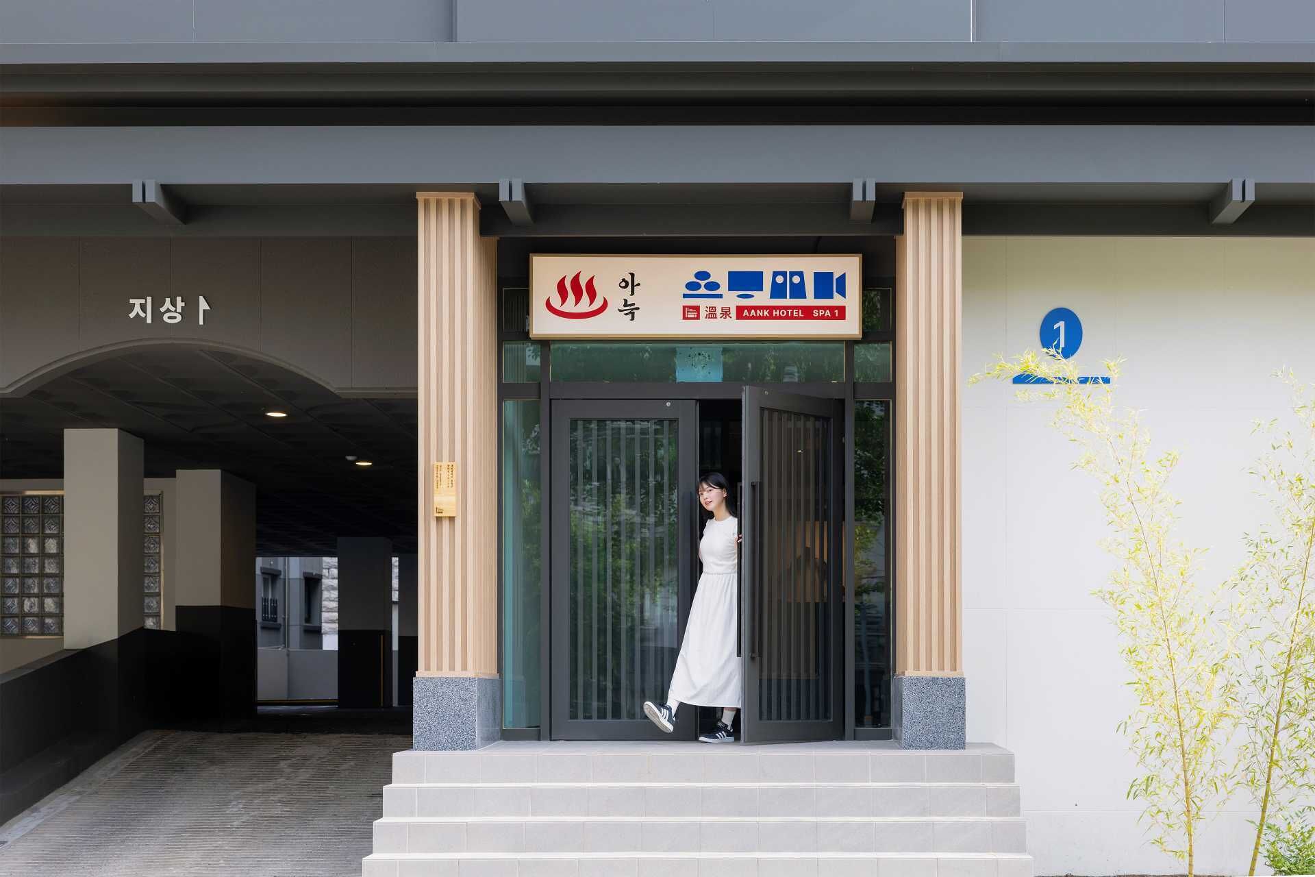 The entrance to AANK HOTEL SPA 1 with a woman stepping out.