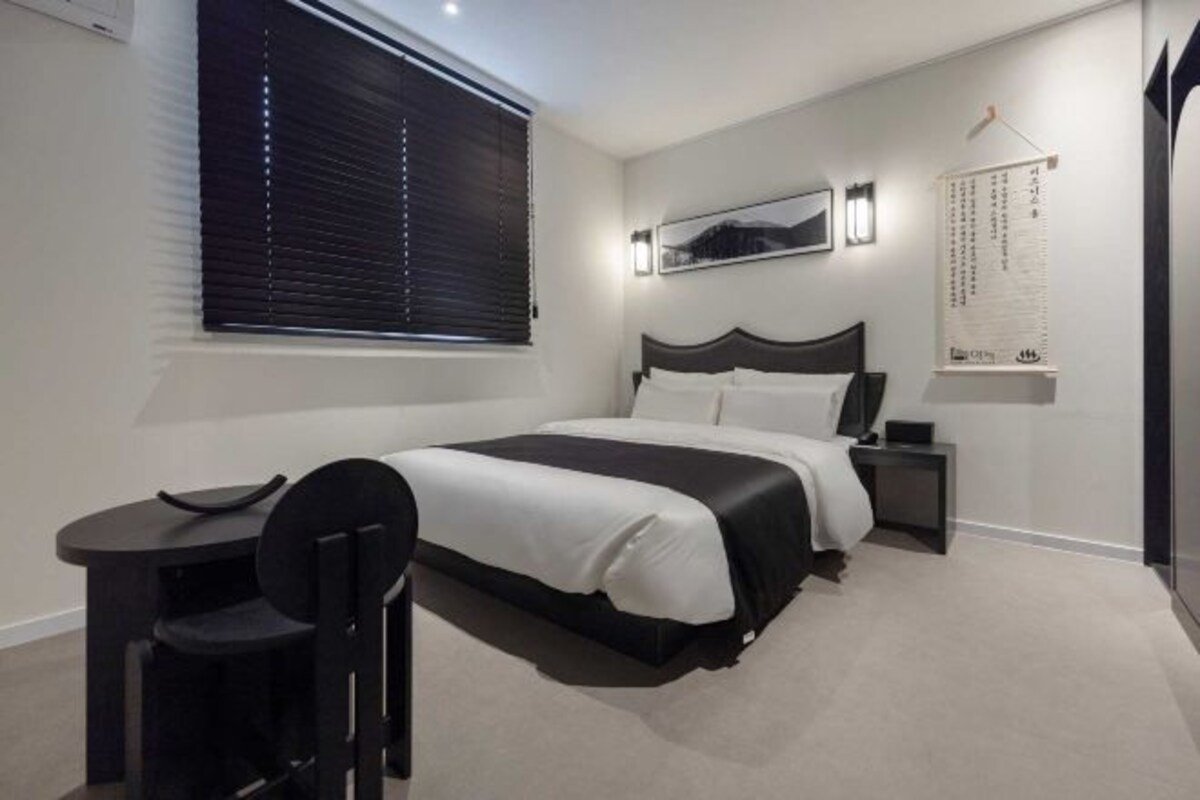 A modern bedroom with a large bed, a small desk, and a chair.
