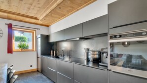 Una cocina moderna con electrodomésticos de acero inoxidable, techo de madera y vistas al exterior.