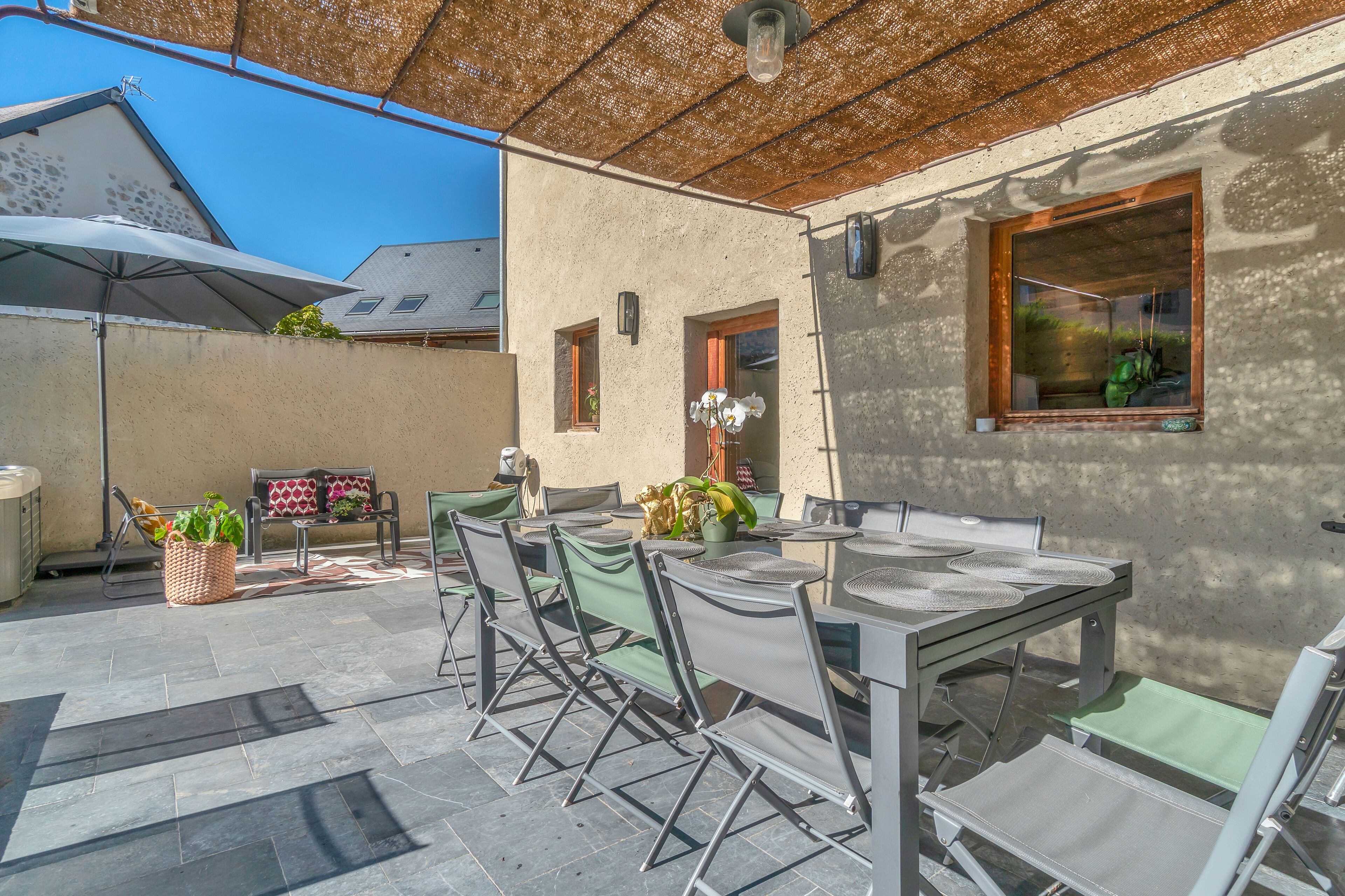 An outdoor patio with a table and chairs, a pergola, and a view of the sky.