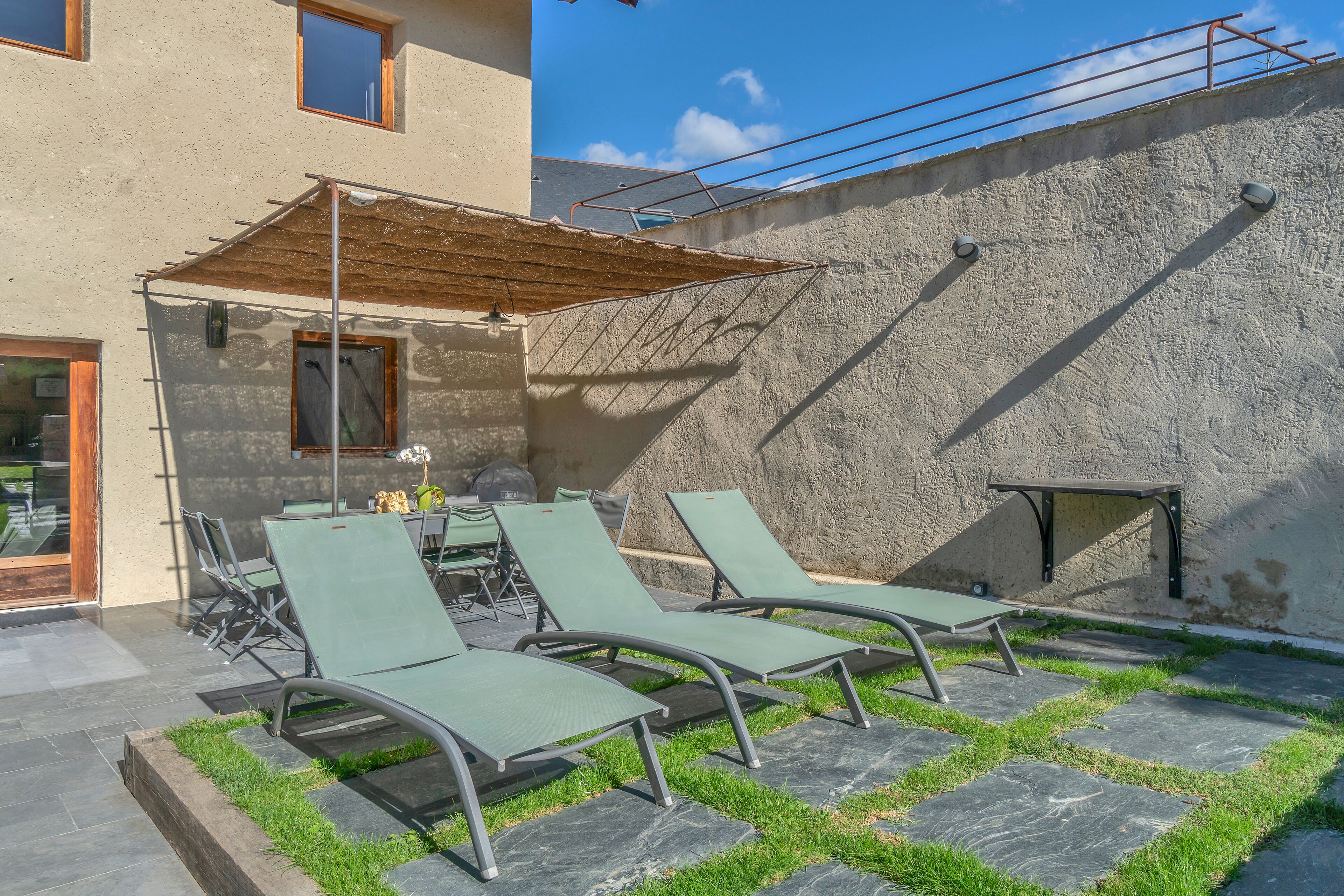 Un patio con tres sillones, una mesa y una pérgola de madera.