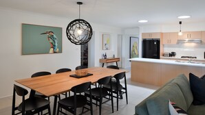 Et moderne køkken med en central ø, et træspisebord og sorte stole.