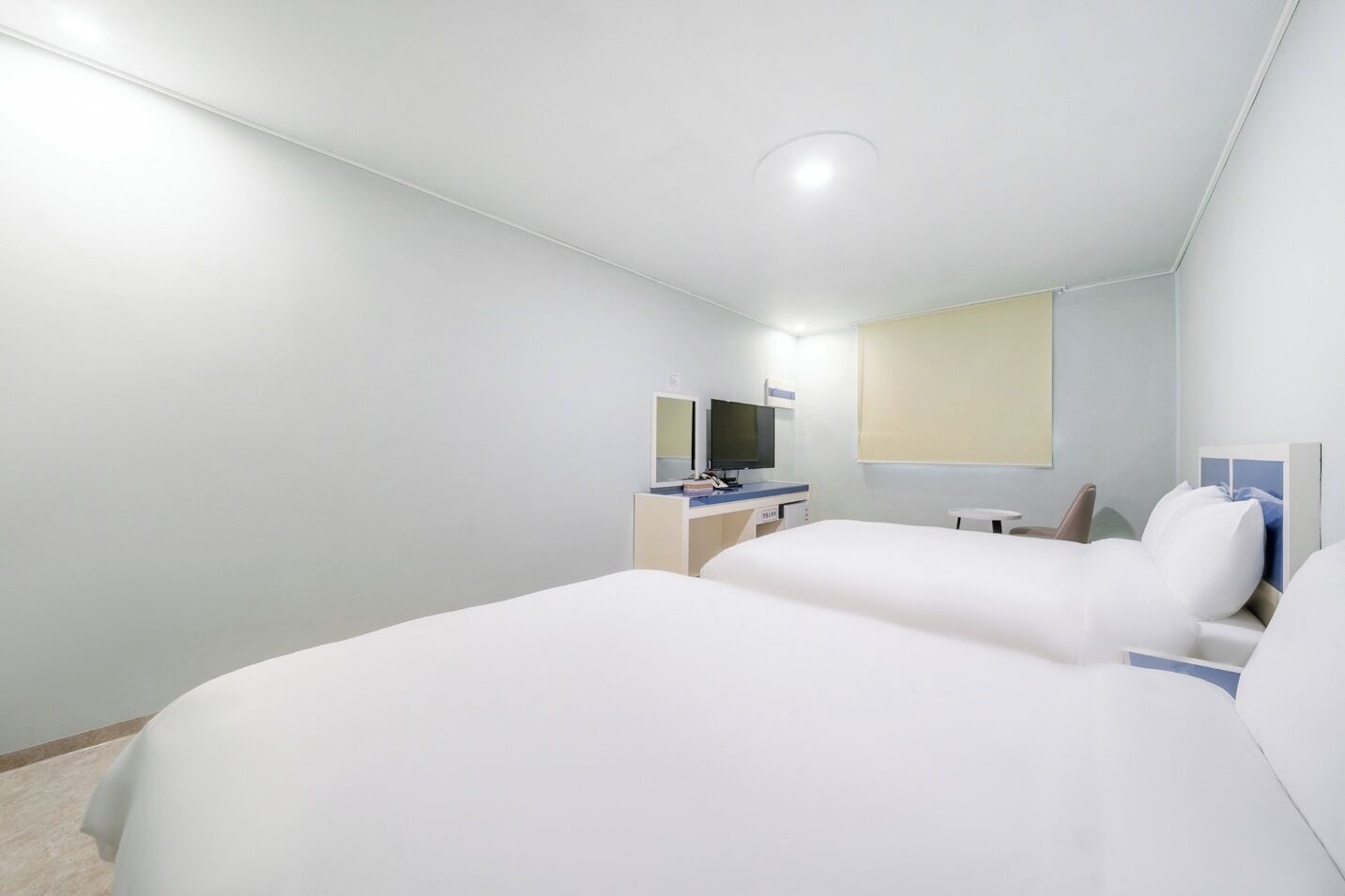 Habitación de hotel con dos camas, un escritorio con computadora y un espejo grande.