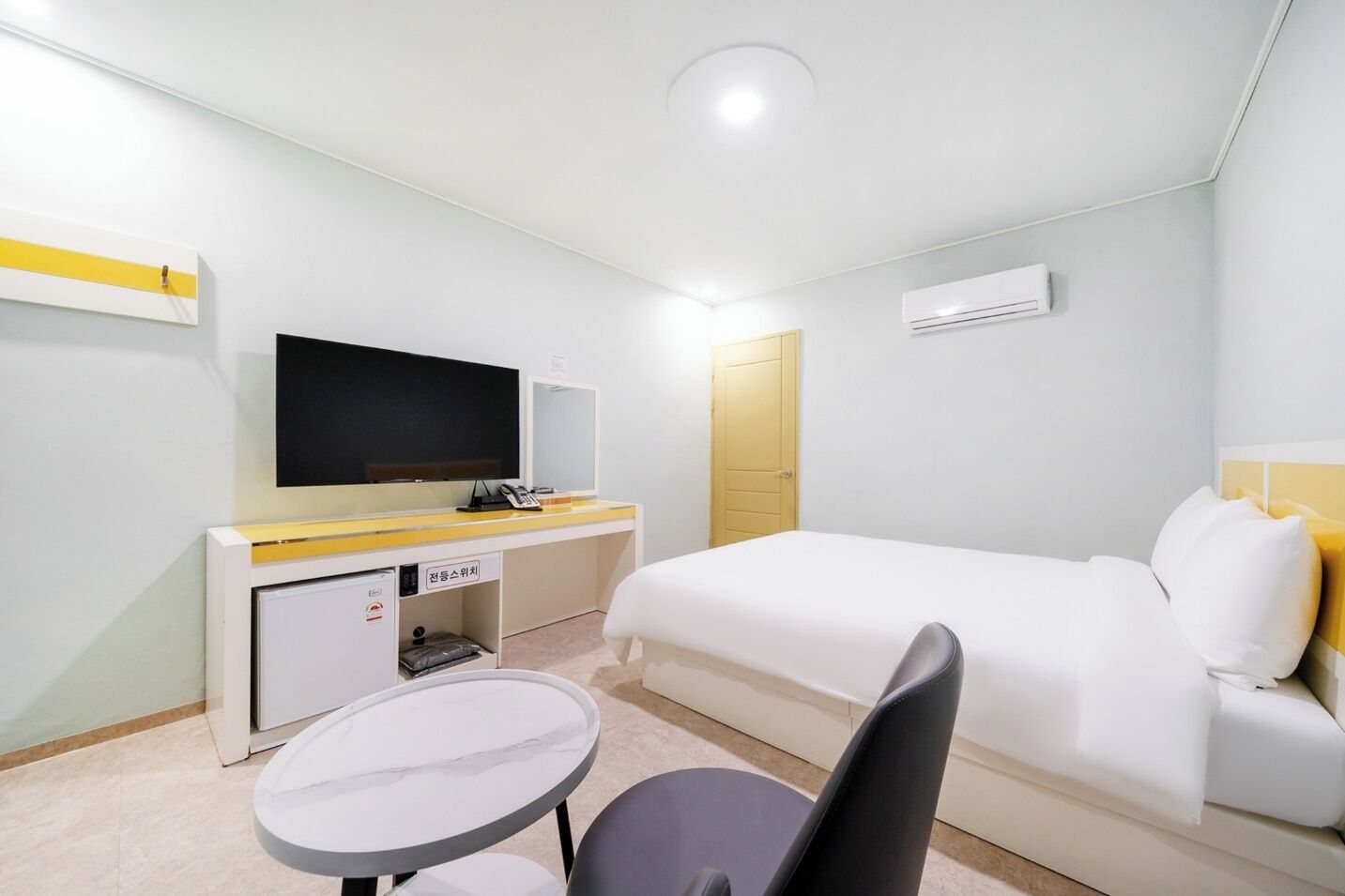 Habitació d'hotel amb un llit, una escriptori amb televisió de pantalla plana, una taula petita i una cadira.