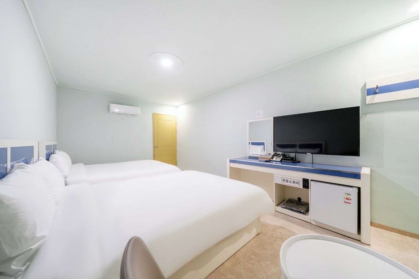 A hotel room with a large bed, a desk with a flat-screen TV, a small cabinet, and a bathroom.