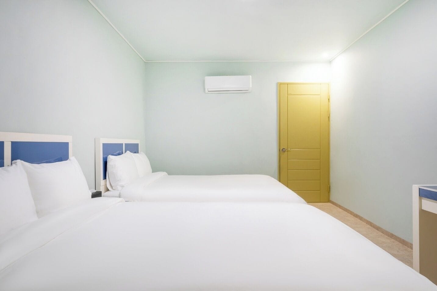 Una habitación de hotel con dos camas, una mesita de noche, un armario y un equipo de aire acondicionado.