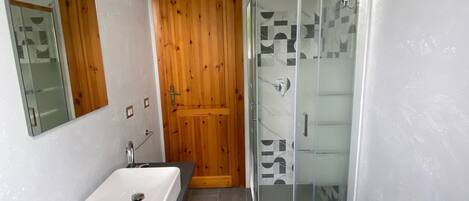 Une salle de bain moderne avec une porte en bois, une douche en verre et deux lavabos.