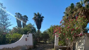 Una entrada con portón y un camino de tierra que lleva a un edificio.