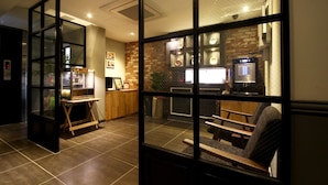 Un moderno vestíbulo de hotel con una recepción, una zona de estar y vistas a través de un separador de vidrio.