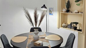 Ein runder Esstisch mit vier Stühlen, eine Vase mit Trockenpflanzen, eine Lampe und eine kleine Schachtel auf dem Tisch.