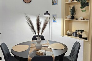 A round dining table with four chairs, a vase with dried plants, a lamp, and a small box on the table.