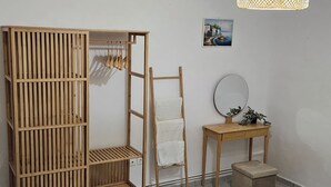 Ein Zimmer mit einem Holzschrank, einer Leiter, einem kleinen Tischchen mit Spiegel und einem Bild an der Wand.