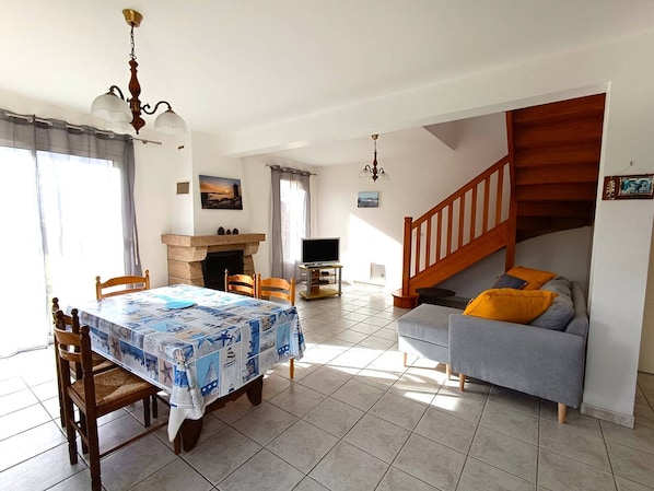 A spacious living area with a dining table, sofa, fireplace, and staircase.
