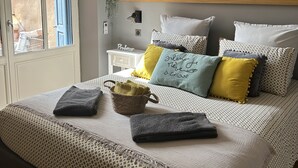 Ein Schlafzimmer mit Bett, Kissen, einem Nachttisch, einer Wandablage und einem Fenster.