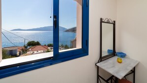 A room with a large window offering a view of the sea and distant mountains. - Natassa Apartments, 2 Bedrooms 30m from sea (Kefalonia)