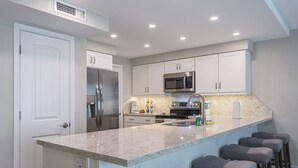 Una cocina moderna con una isla grande, electrodomésticos de acero inoxidable y taburetes de bar.