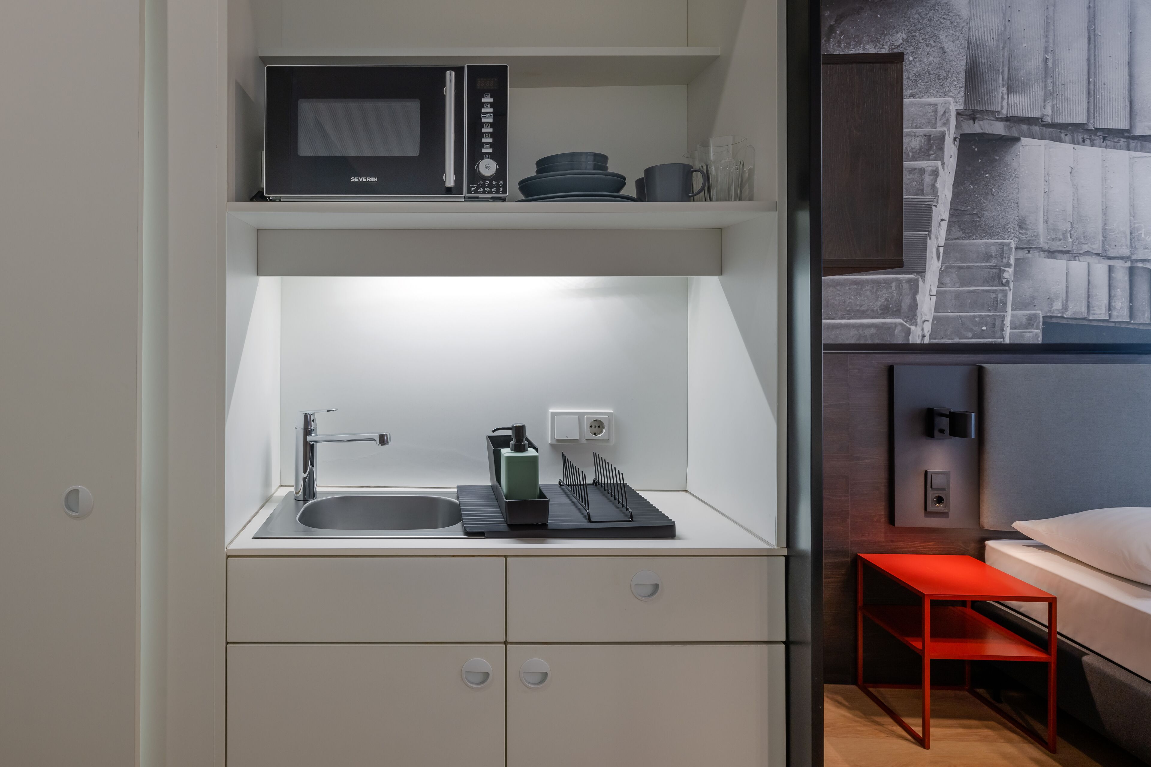 Une cuisine compacte équipée d’un four à micro-ondes, d’un évier et de placards de rangement.