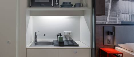 A compact kitchen with a microwave, sink, and storage cabinets.