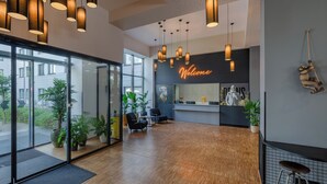 Una moderna zona de recepción con un cartel de 'Welcome', suelo de madera y varias lámparas colgantes.