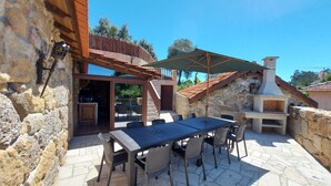 An outdoor patio with a stone table and chairs, a barbecue grill, and a wooden pergola. - For families who love nature and the countryside. (Celorico de Basto)