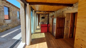 A rustic interior with stone walls, wooden flooring, and a stone fireplace. - For families who love nature and the countryside. (Celorico de Basto)