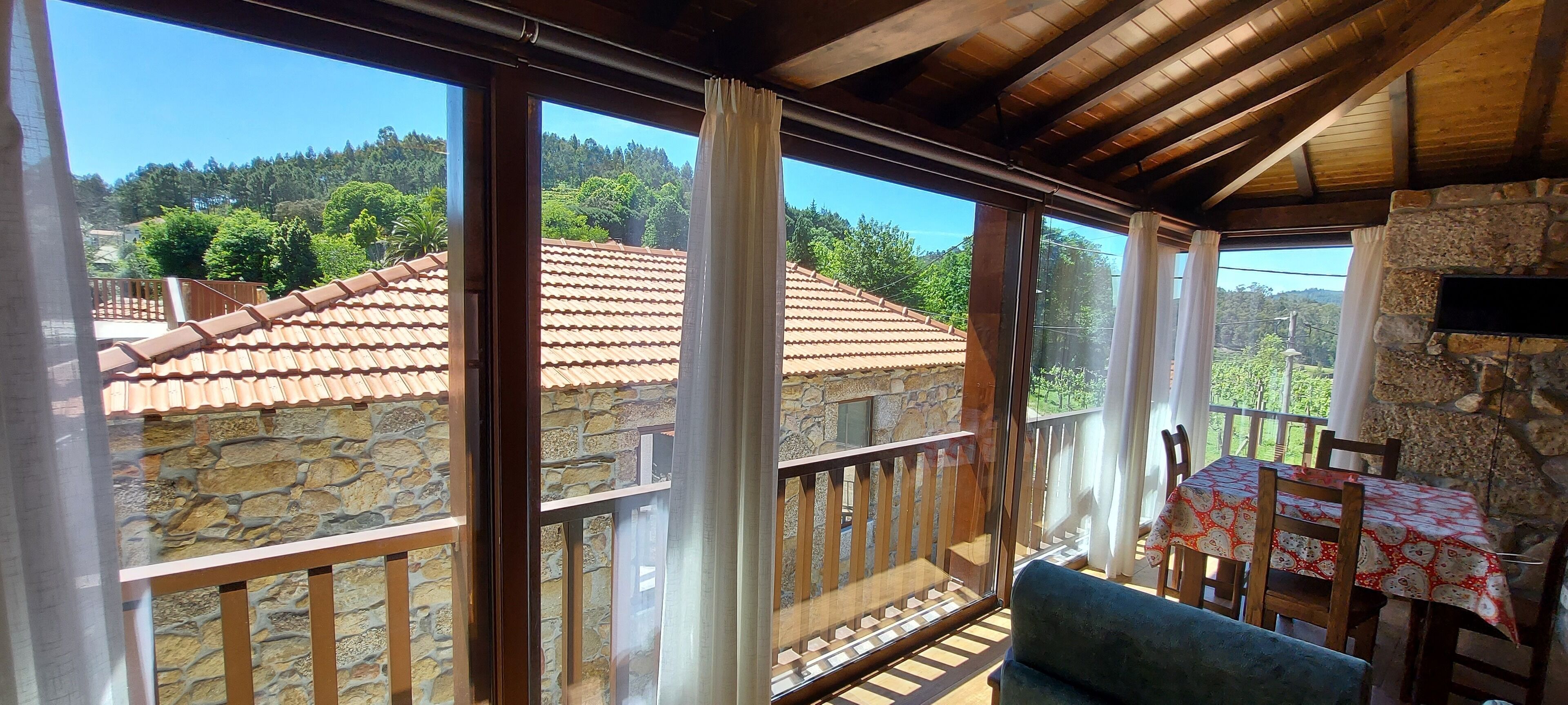 Ein Balkon mit einer Steinmauer, einem Tisch mit gemustertem Tischläufer und einem Stuhl.