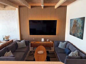 A modern living room with two sofas, a coffee table, a TV, and a wooden accent wall.