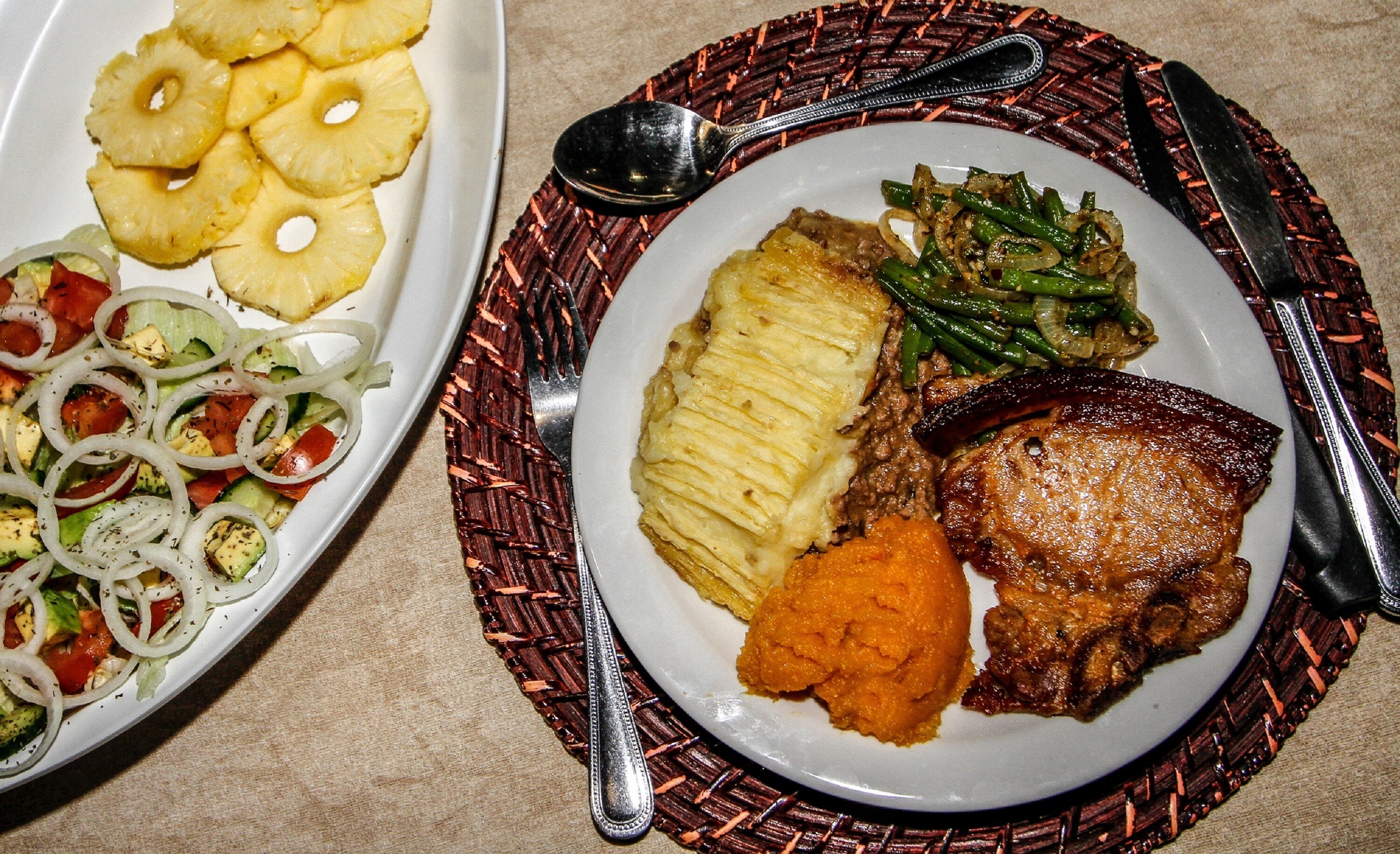 Un plato con una variedad de comida, incluyendo un plato de carne, puré de papas y judías verdes.