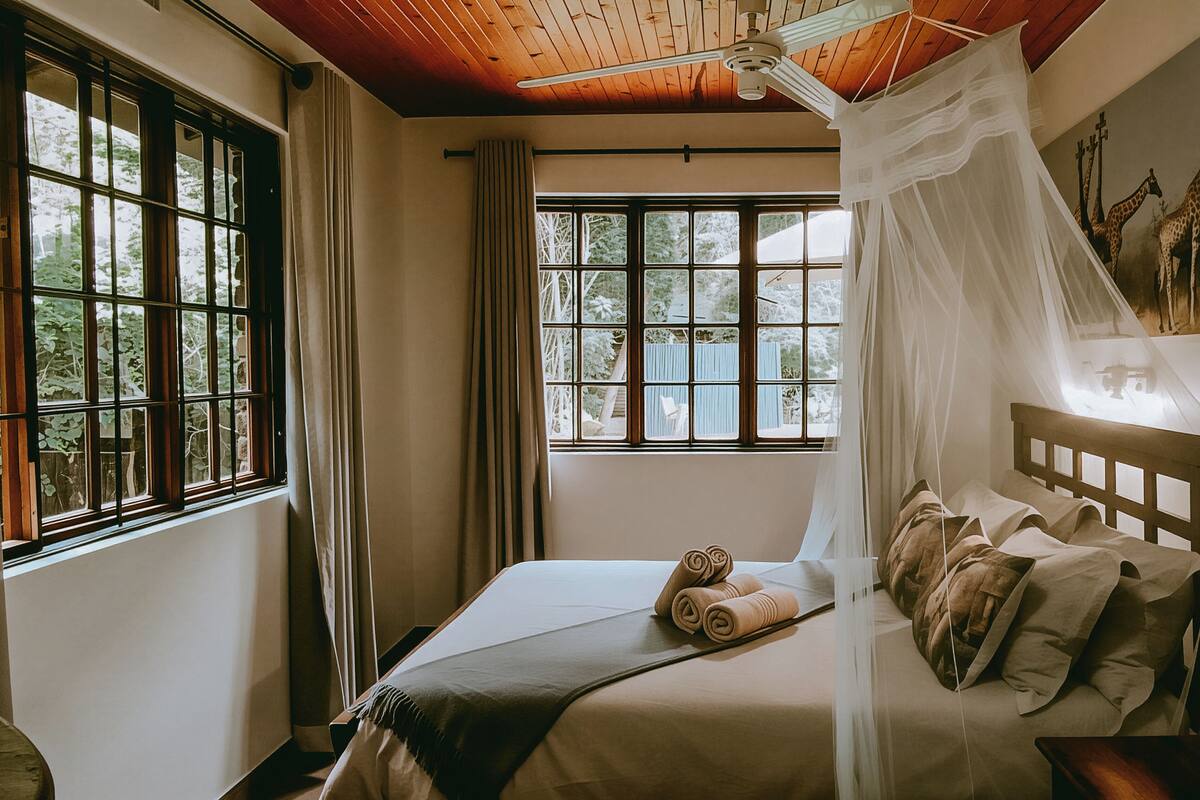 Ein Schlafzimmer mit Bett, Fenster und Deckenventilator.
