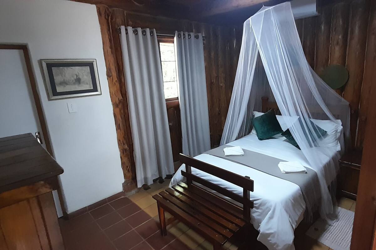 Ein Zimmer aus Holz mit einem Bett, einer Bank und einem kleinen Tisch.