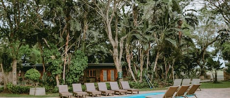 A pool area with lounge chairs and a building in the background.