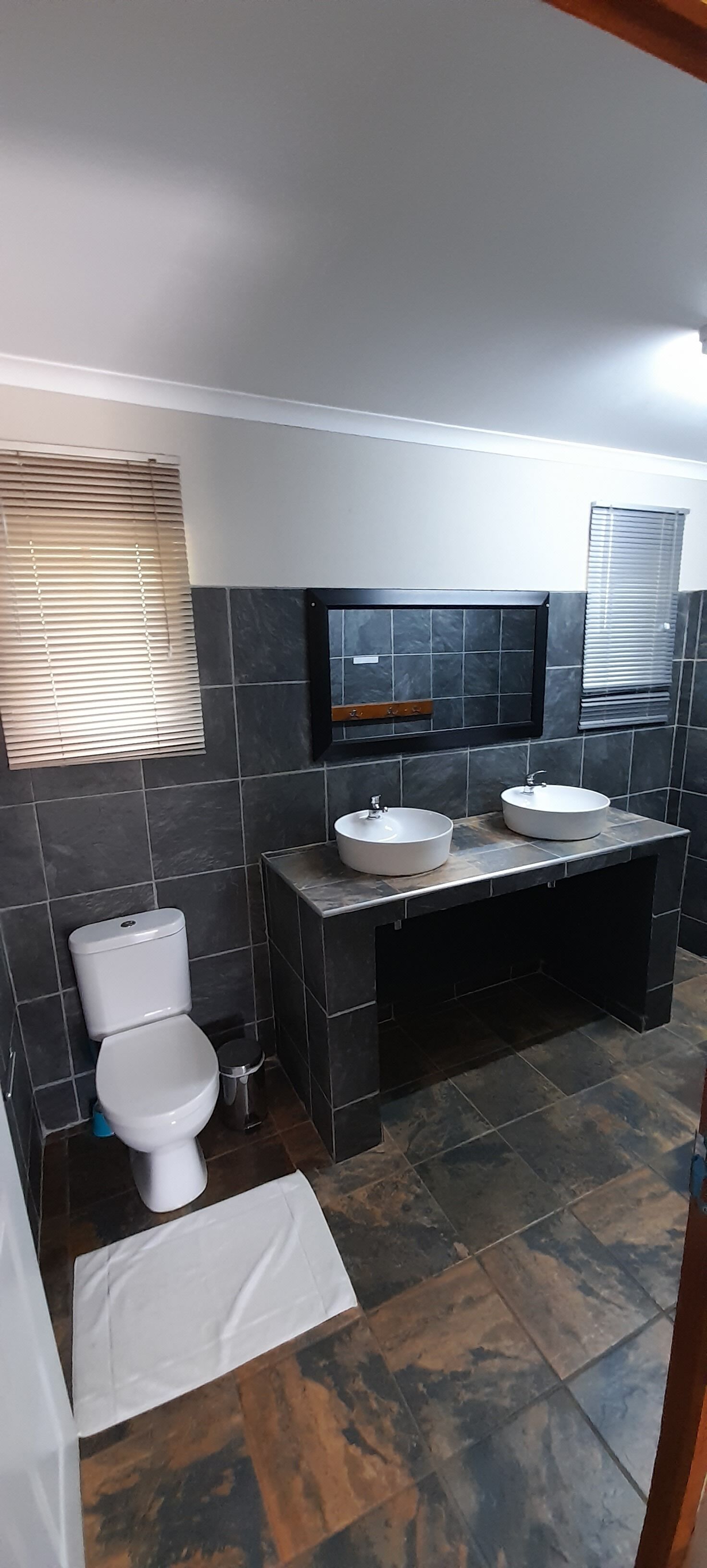 Un baño moderno con dos lavamanos, un inodoro y un mueble de tocador.