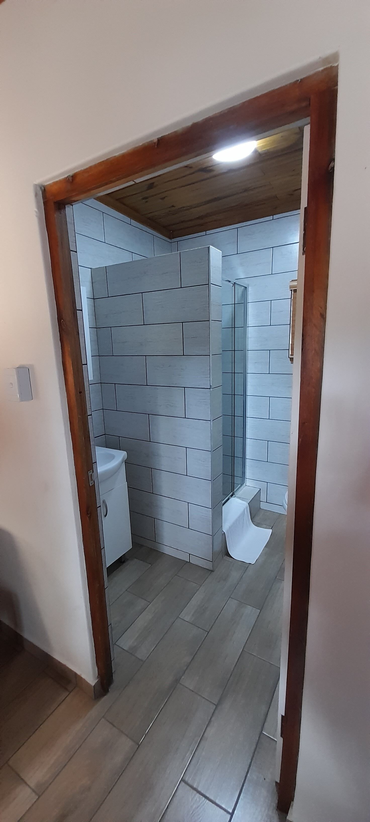 A bathroom with tiled walls, a sink, and a shower.