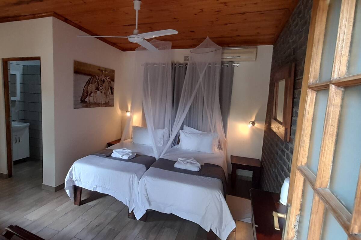 Ein Schlafzimmer mit Bett, Deckenventilator, Nachttisch und Fenster mit Ausblick.
