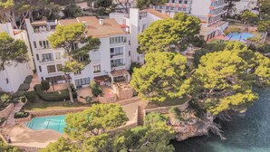 Vista aérea de una propiedad costera con piscina, jardines en terrazas y vistas al mar.