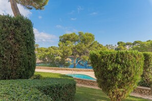 A landscaped garden with a swimming pool, surrounded by neatly trimmed hedges and trees.