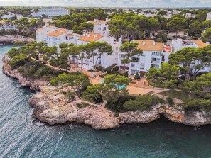 Una propiedad costera con varias edificaciones, un litoral rocoso y un mar azul cristalino.