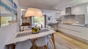 Una cocina moderna con armarios blancos, una isla grande y una lámpara colgante.