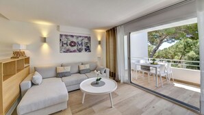 Una sala moderna con un sofá, una mesa redonda de centro y un balcón con zona de comedor.