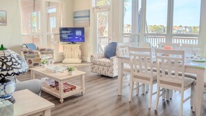 A spacious living room with a television, comfortable seating, and large windows offering a view of the sea. - [Summer Deals on remaining dates] 3 min to Beach! Waterfront, Pool, Beach gear (Destin)