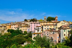 A hillside town with historic buildings, a prominent clock tower, and lush greenery. - La Casa Toscana - Apt Castello 7 km by the sea (Castagneto Carducci)