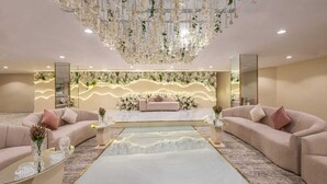 A luxurious room with a large chandelier, a sofa, a coffee table, and a decorative wall.