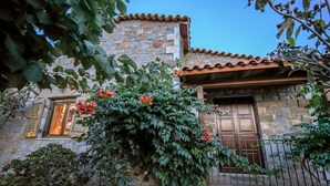 A stone building with a tiled roof, a wooden door, and a window with shutters. - Anthis Cottage (Malevizi)