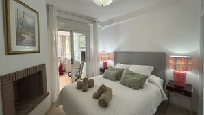 A bedroom with a large bed, a fireplace, a door leading to a balcony, and a ceiling light. - Calahonda Royale Apartment Edif Lirio, Mijas Costa by Holidays & Home (Malga)