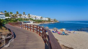 A wooden boardwalk leading to a beach with umbrellas and lounge chairs. - Calahonda Royale Apartment Edif Lirio, Mijas Costa by Holidays & Home (Malga)