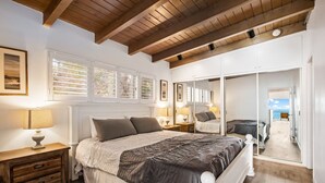 Une chambre à coucher avec un grand lit, des tables de chevet, une armoire et un miroir.